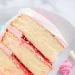 1Slice of a mermaid-themed 3 layer vanilla cake with chocolate mermaid tails and seashells on a white plate.