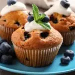 1Plate of tasty muffins and blueberries on marble table, closeup